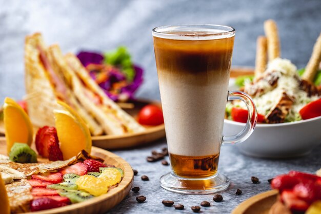 Seitenansicht heißes Getränk mit Kaffeemilchhonig und Kaffeebohnen auf dem Tisch