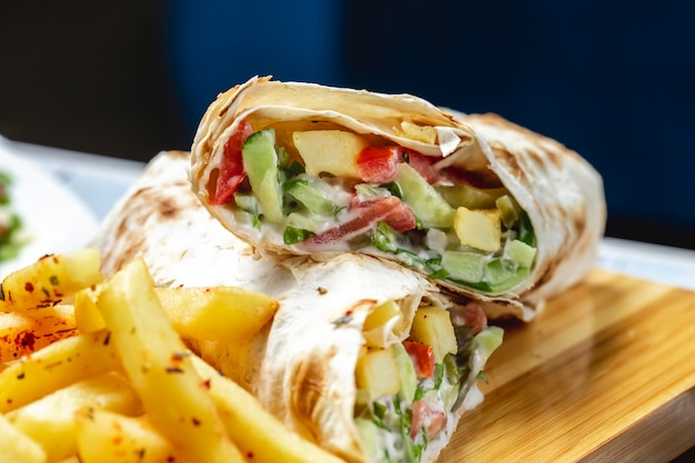 Kostenloses Foto seitenansicht hühnerdöner mit mayo-gurkentomaten-salat und pommes frites auf dem tisch