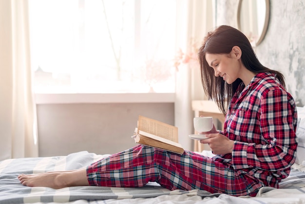 Kostenloses Foto seitenansicht junge frau, die das lesen eines buches genießt