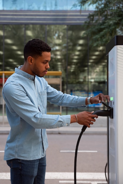 Seitenansicht junger Mann, der Elektroauto auflädt