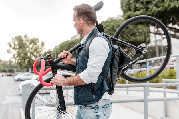 Seitenansicht junger Mann, der sein Fahrrad hält