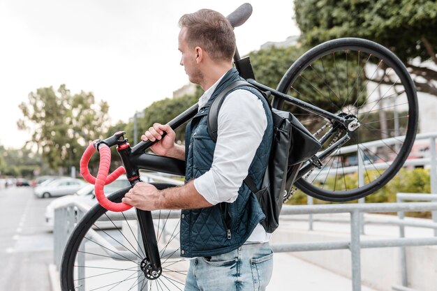 Seitenansicht junger Mann, der sein Fahrrad hält