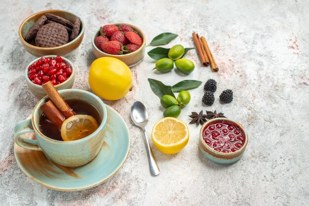 Seitenansicht Kekse und Beeren Zimt die appetitlichen Kekse Erdbeeren Samen von Granatapfel Zitrone Löffel eine Tasse Tee Zitrusfrüchte auf dem Tisch