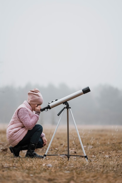 Seitenansicht Kind mit einem Teleskop außerhalb