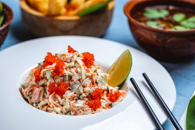 Seitenansicht Krabbensalat Gurke Reiskrabbenfleisch Tobiko Kaviar Mayo und Limettenscheibe auf einem Teller