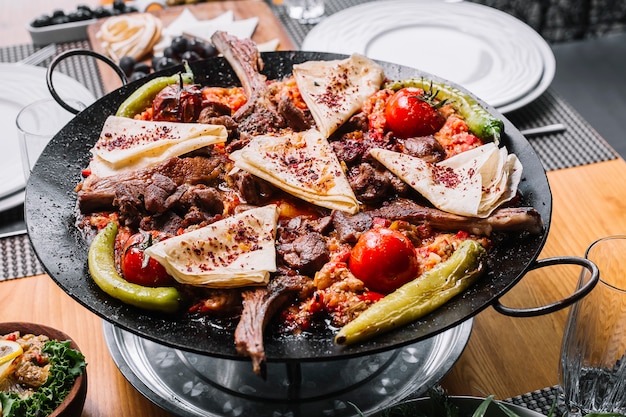 Seitenansicht Lamm Saj gegrillte Lammrippen mit Zwiebel Paprika Tomaten scharfen grünen Pfeffer und Pita mit getrockneten Berberitzen