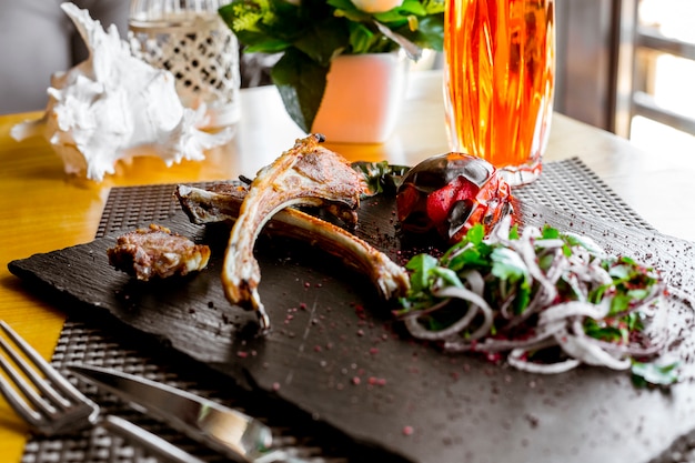 Seitenansicht Lammrippen Kebab mit gegrillten Tomaten und Zwiebeln mit Kräutern