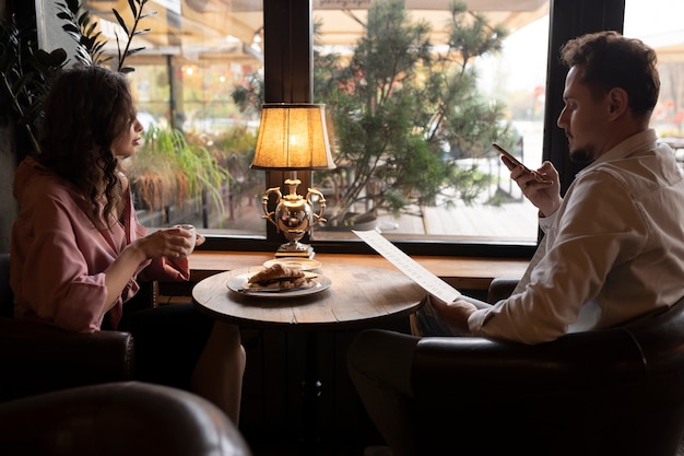 Kostenloses Foto seitenansicht leute, die im restaurant sitzen