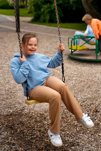 Kostenloses Foto seitenansicht mädchen mit down-syndrom auf schaukel