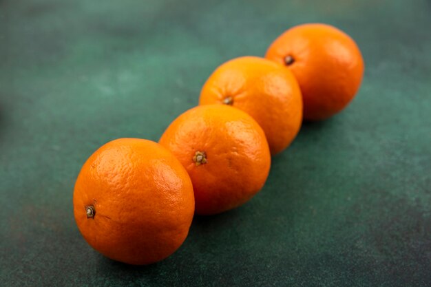 Seitenansicht Mandarinen auf einem grünen Hintergrund