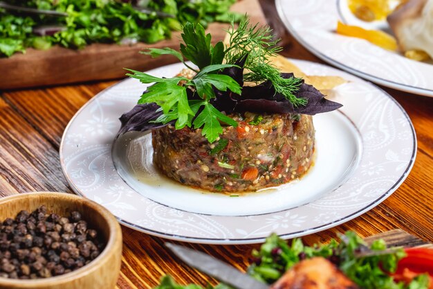 Seitenansicht Mangal Salat geröstete Auberginen Paprika Zwiebel Tomatengrün und schwarzer Pfeffer auf dem Tisch