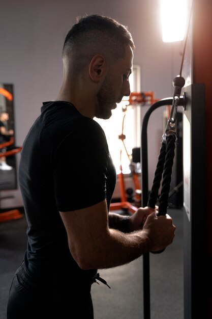 Seitenansicht Mann, der im Fitnessstudio trainiert