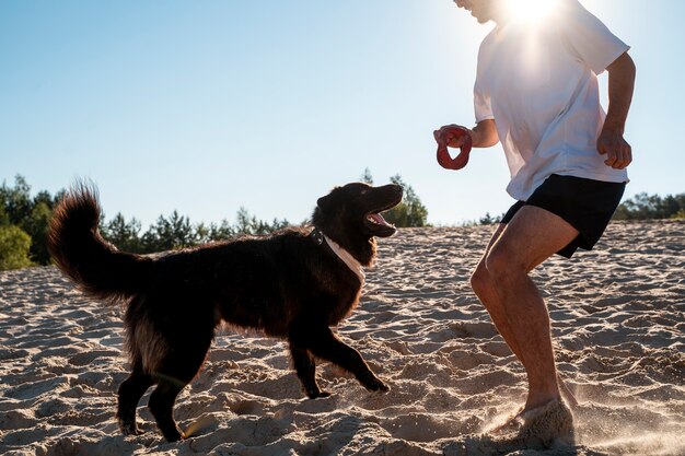 Seitenansicht Mann spielt mit Hund am Strand