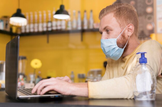 Seitenansicht moderner Mann, der unter Verwendung der medizinischen Maske arbeitet