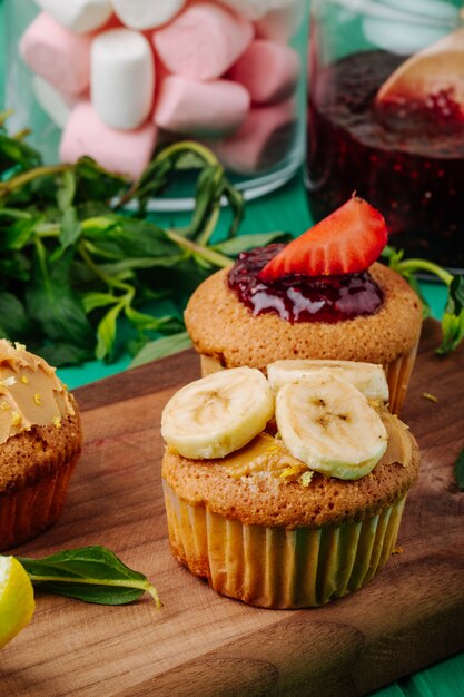 Seitenansicht Muffins mit Erdbeerbanane auf einem Brett mit Minze