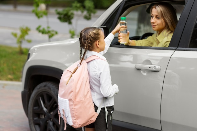 Kostenloses Foto seitenansicht mutter, die mädchen zur schule fährt