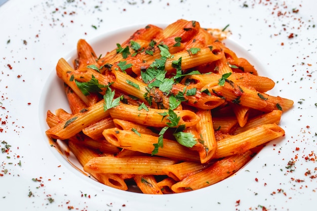 Kostenloses Foto seitenansicht penne pasta mit tomatensauce und gemüse auf einem teller