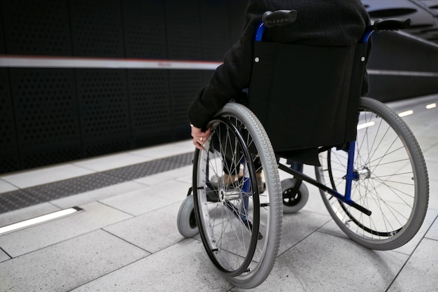 Seitenansicht Person im Rollstuhl an der U-Bahnstation