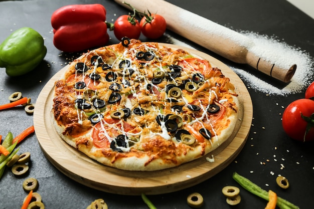 Seitenansicht Pizza auf einem Stand mit Tomaten Oliven und Paprika