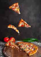 Kostenloses Foto seitenansicht pizza mit pfeffer und tomaten und pizzastücken in bordkochgeschirr