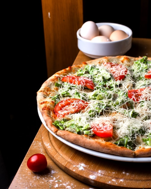 Seitenansicht Pizza mit Tomaten und Eiern auf dem Tisch