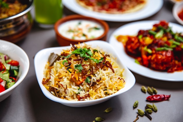 Seitenansicht Reisgarnitur mit gebratenem Zwiebel-Karotten-Gemüse und Chili-Pfeffer auf dem Tisch