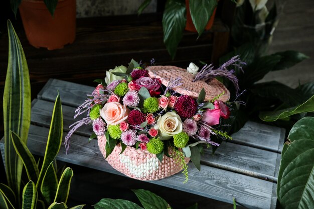 Seitenansicht Rosenstrauß mit Wildblumen in einem rosa Korb