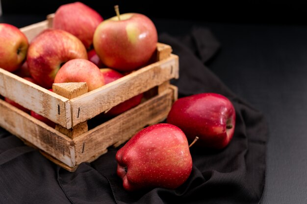 Seitenansicht rote Äpfel in Kiste mit schwarzem Tuch