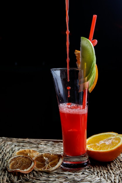 Seitenansicht roter Fruchtsmoothie mit Tubuli für Getränke und getrocknete Zitrone und Tropfen in Servietten