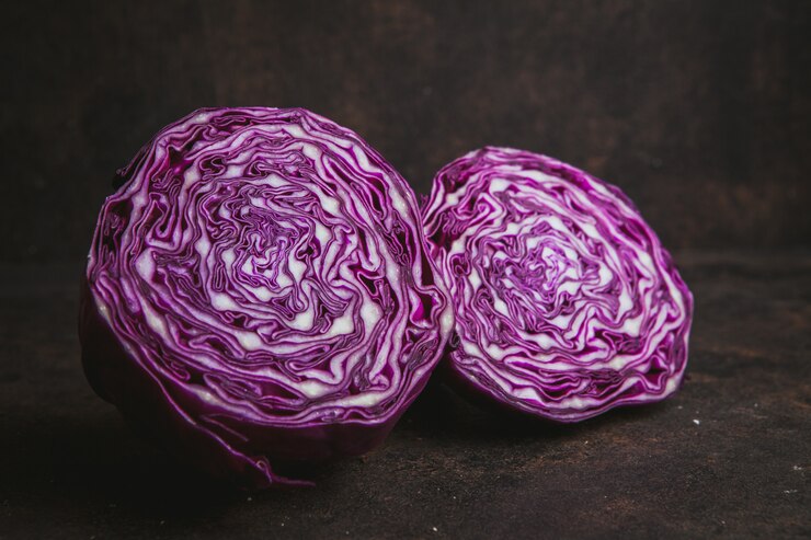 Kostenlose Foto seitenansicht rotkohl halbiert auf dunkelbraun.