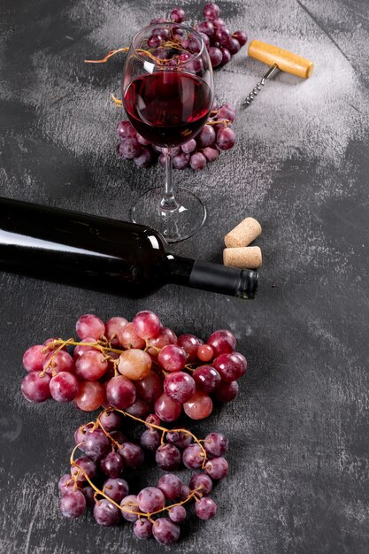 Seitenansicht Rotwein mit Traube auf schwarzem Stein vertikal