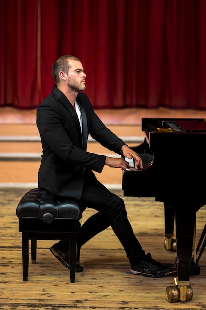 Kostenloses Foto seitenansicht sitzender musiker, der klavier spielt