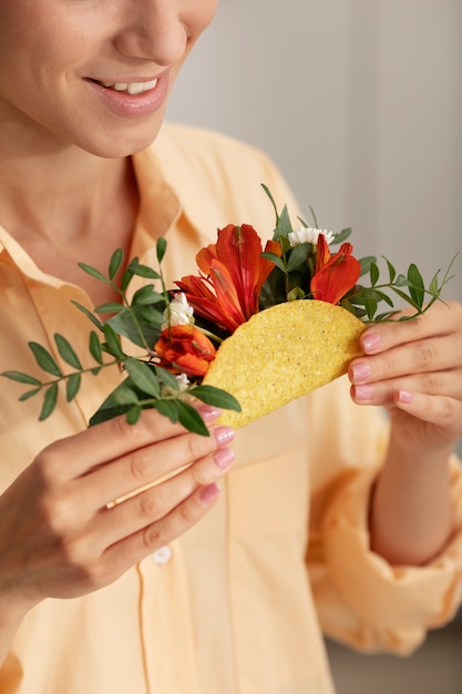 Kostenloses Foto seitenansicht-smiley-erwachsener, der taco mit blumen hält