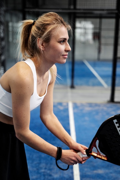 Kostenloses Foto seitenansicht sportliche frau, die paddle-tennis spielt