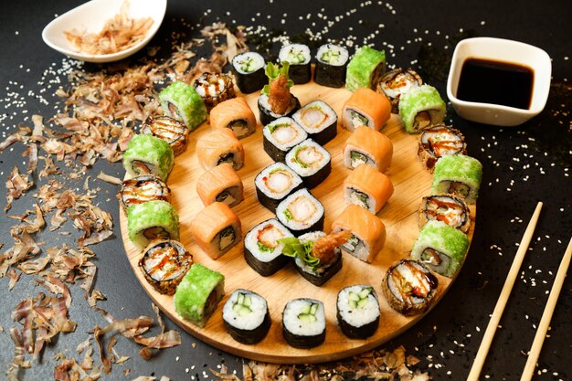 Seitenansicht Sushi-Rollen auf einem Tablett mit Ingwer-Wasabi und Sojasauce mischen