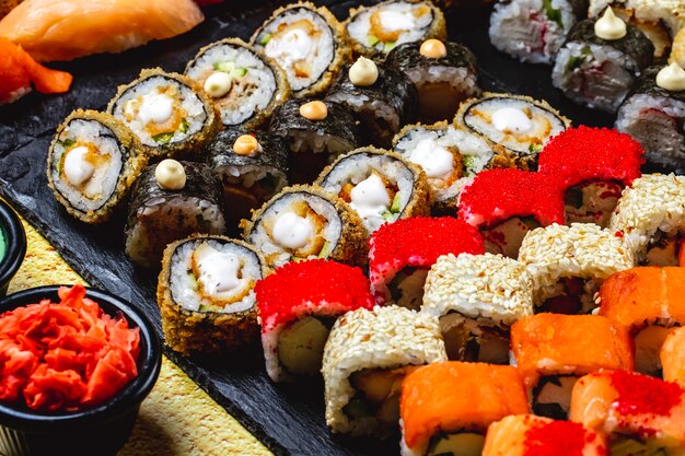 Seitenansicht Sushi Set Alaska Roll Chuckien Hot Roll Kalifornien mit Krabbenfleisch und Tobiko Kaviar Maki und Philadelphia mit Frischkäse auf einem Tablett