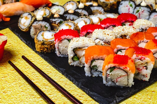 Seitenansicht Sushi Set Huhn Hot Roll Huhn Alaska Roll Kalifornien mit Krabbenfleisch und Tobiko Kaviar Philadelphia mit Krabbenfleisch und Frischkäse auf einem Tablett