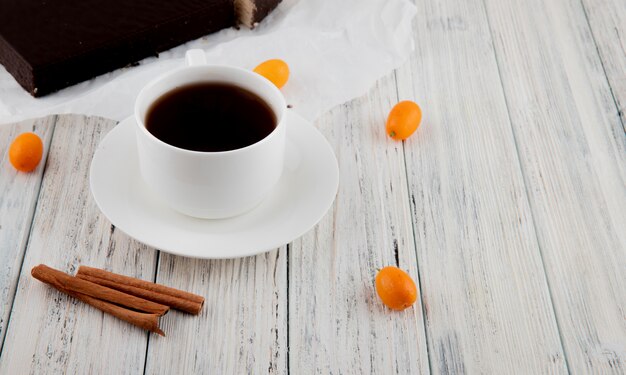 Seitenansicht Tasse Kaffee mit Zimt-Kumquat und knusprigem Waffelkuchen auf weißem Holztisch