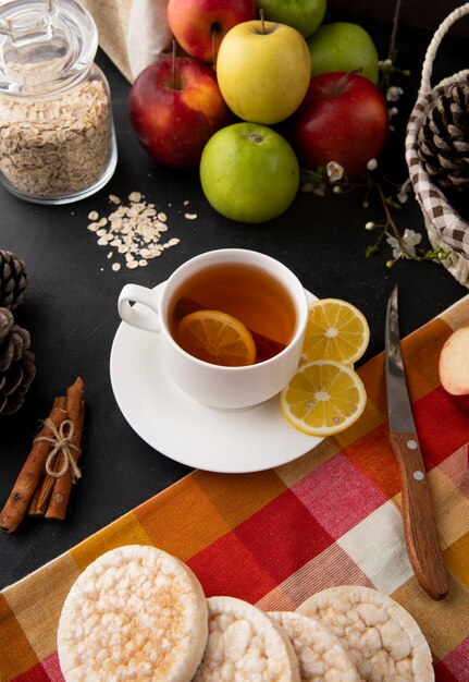 Seitenansicht Tasse Tee mit geschnittener Zitrone und Zimt mit Äpfeln und einem Messer auf dem Tisch