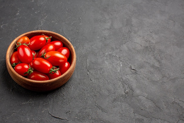 Seitenansicht Tomaten Holzschale mit reifen roten Tomaten auf der linken Seite des dunklen Tisches