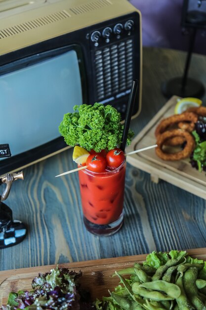 Seitenansicht Tomatensaft mit Tomaten Zitrone und Kräutern in einem Glas