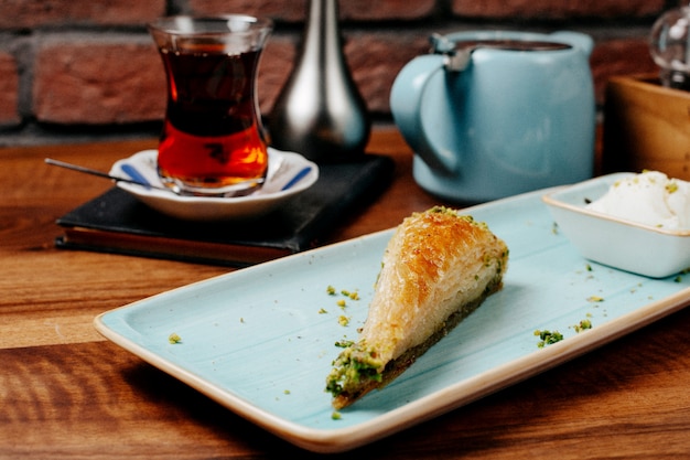 Kostenloses Foto seitenansicht traditionelles türkisches dessert pistazien-baklava mit eiscreme mit einem glas tee