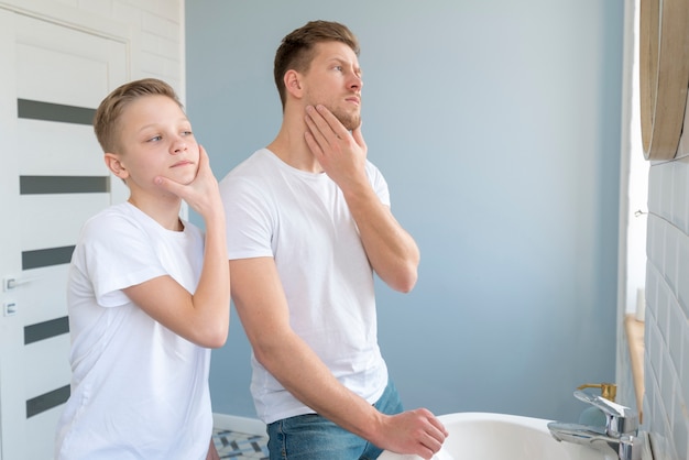 Seitenansicht Vater und Sohn schauen in den Spiegel