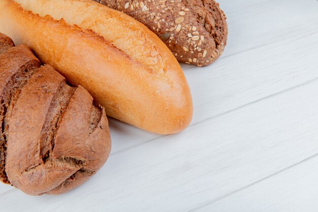 Seitenansicht von Broten als vietnamesisches und schwarzes Baguette und Schwarzbrot auf Holztisch mit Kopierraum