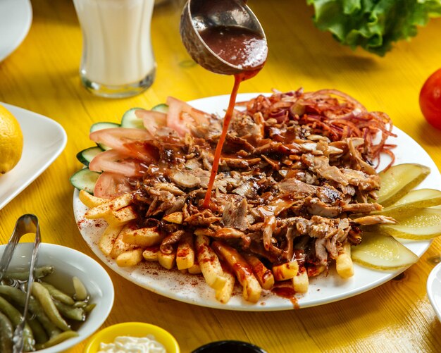 Seitenansicht von Chiken Döner Kebab auf dem Teller mit Brot Pommes Frites Tomaten Zwiebeln Gurken und Salat