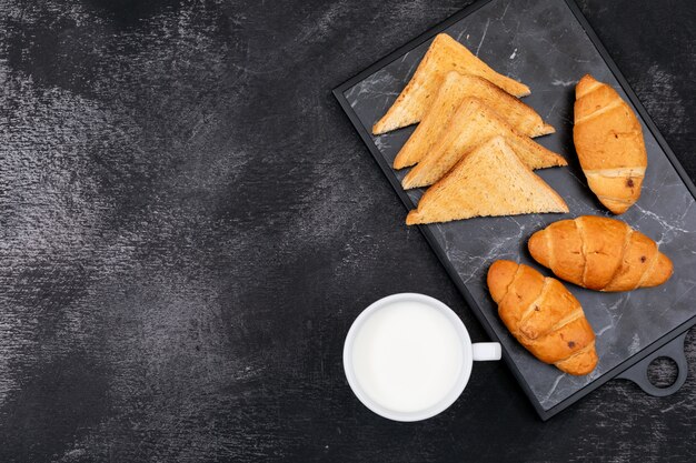 Seitenansicht von Croissants mit Toast und Milch und Kopierraum auf schwarzem Hintergrund horizontal