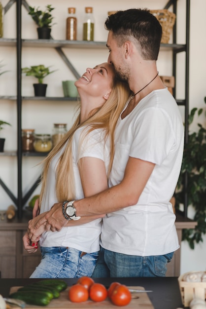 Kostenloses Foto seitenansicht von den jungen liebevollen paaren, die hinter dem küchenarbeitsplatz stehen