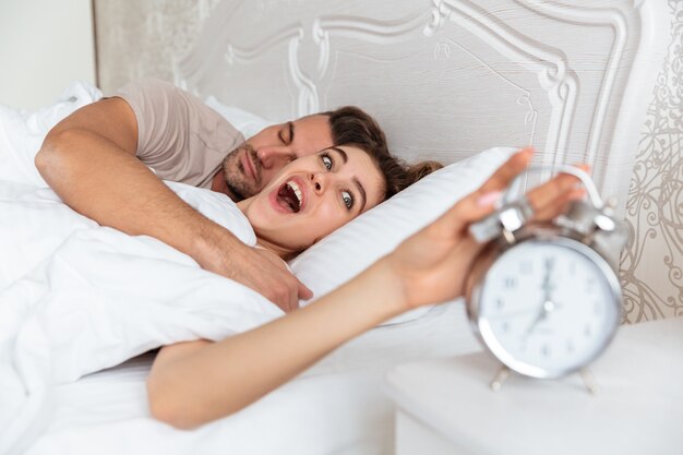 Seitenansicht von den überraschten reizenden Paaren, die zusammen im Bett schlafen
