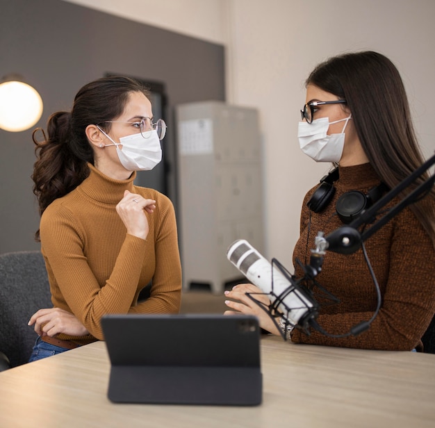 Seitenansicht von Frauen mit medizinischen Masken, die eine Radiosendung tun