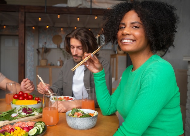 Kostenloses Foto seitenansicht von freunden, die lachsschüsseln essen